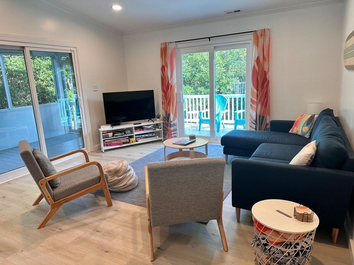 Roomy living room with books, board games, comfy throws, a 50" smart TV, and easy access to the back deck anytime you just want to listen to the waves.